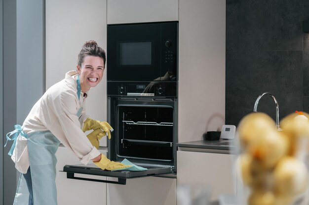 Femme au foyer en gants jaunes nettoyant la cuisine