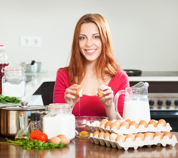 Femme au foyer avec des oeufs dans la cuisine de la maison