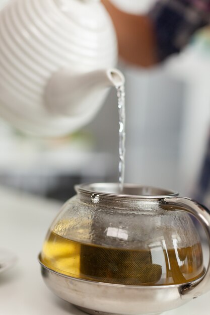 Femme au foyer préparant du thé vert naturel pour le petit déjeuner dans la cuisine