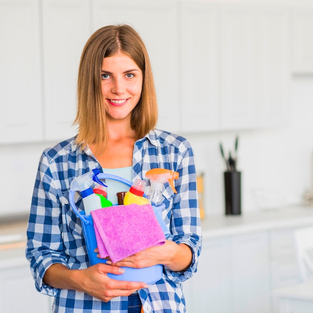 Femme au foyer souriante tenant l&#39;équipement de nettoyage dans les mains