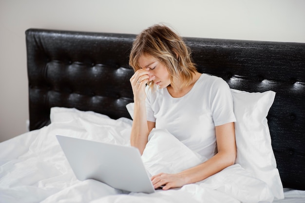 Femme au lit à l'aide d'un ordinateur portable