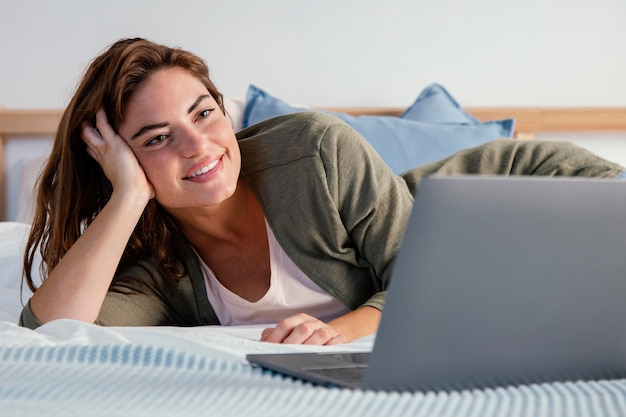 Femme au lit avec ordinateur portable