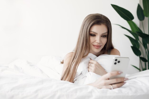 Femme au lit avec un téléphone mobile