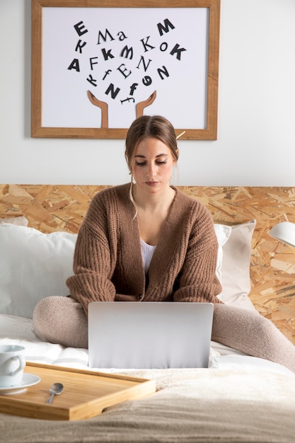 Femme au lit travaillant sur ordinateur portable