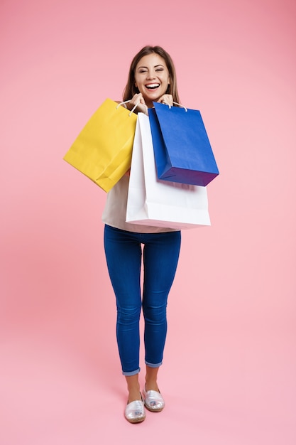 Femme au look basique tenant des sacs après le shopping au centre commercial