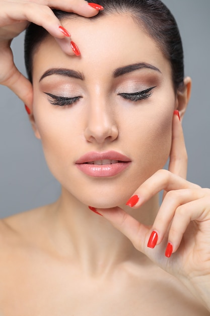 Femme au maquillage nude un vernis à ongles rouge