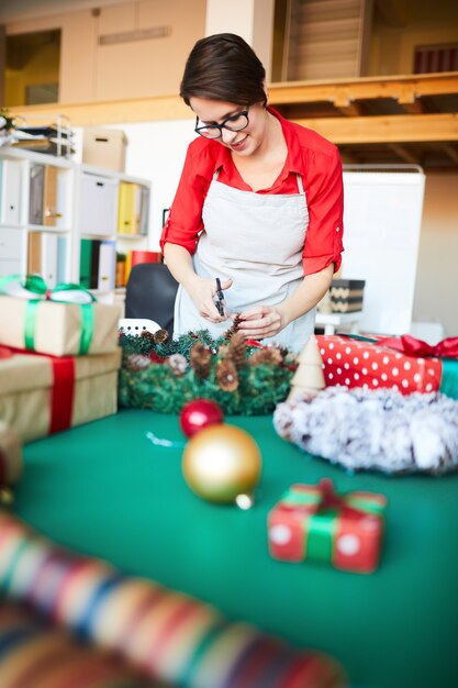 femme au travail, faire une guirlande de Noël et emballer des cadeaux