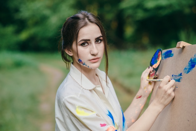 Femme au visage coloré peint dessin sur une toile