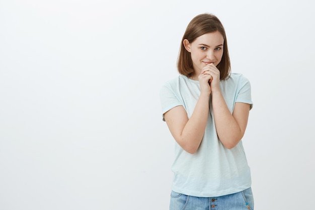 Femme aux cheveux bruns courts tenant les mains sur les lèvres et souriante féminine et mignonne étant amoureuse