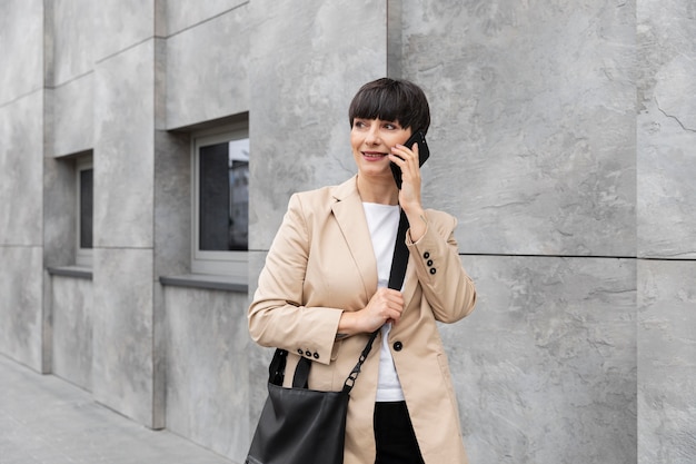 Femme aux cheveux courts parlant au téléphone à l'extérieur