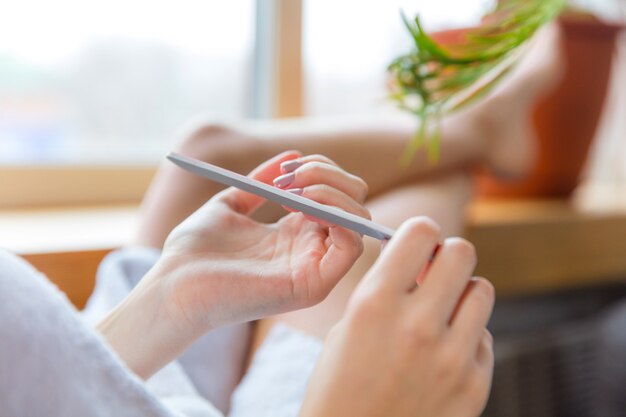 Femme aux cheveux longs portant une serviette faisant sa routine quotidienne de soins de la peau à la maison.