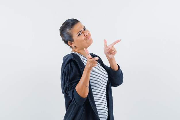 Femme aux cheveux noirs pointant de côté en chemise