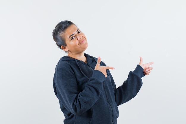 Femme aux cheveux noirs en veste pointant de côté et à la recherche expressive