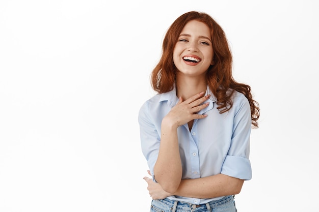 femme aux cheveux rouges, riant et souriant naturel, debout heureux en blouse sur blanc