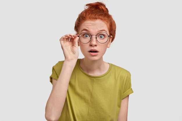 Femme aux taches de rousseur perplexe aux yeux bleus