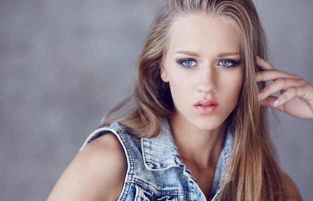 Une femme aux yeux bleus portant une veste en jean.