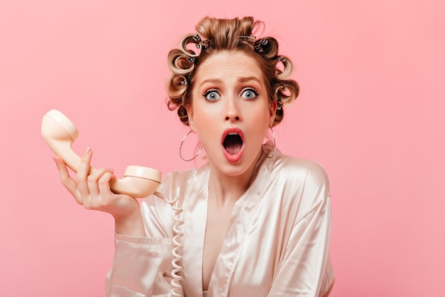 Femme aux yeux bleus regarde devant avec étonnement après avoir parlé au téléphone