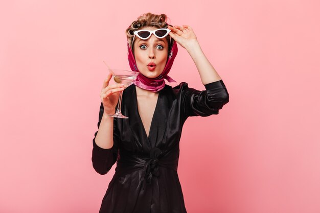 Femme aux yeux gris regarde devant avec surprise et enlève ses lunettes de soleil