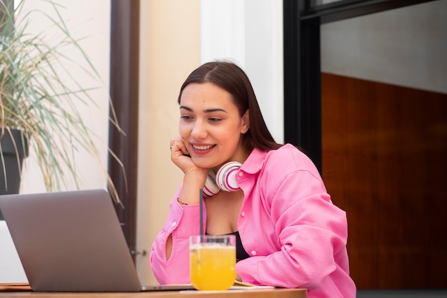 Photo gratuite femme ayant un appel vidéo sur un ordinateur portable dans un café