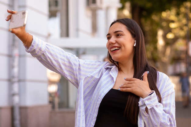 Photo gratuite femme ayant un appel vidéo sur smartphone alors qu'elle est en ville