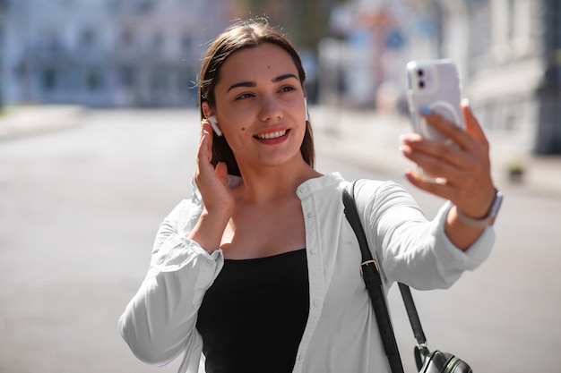 Photo gratuite femme ayant un appel vidéo sur smartphone tout en étant à l'extérieur de la ville