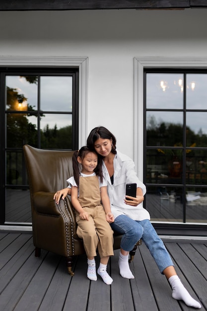 Femme ayant un appel vidéo avec son mari à côté de leur fille à l'extérieur