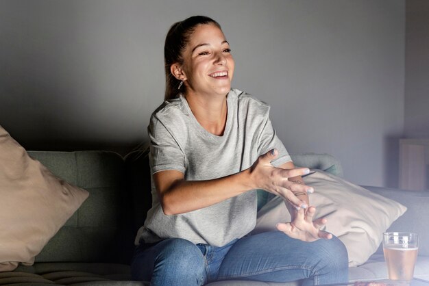 Femme ayant de la bière et des collations à la maison en regardant la télévision