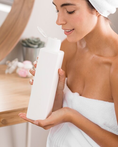 Femme ayant une journée de détente et sentant une lotion pour le corps