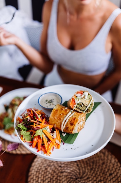 Femme ayant une salade de repas végétarien végétalien sain coloré dans la lumière du jour naturelle de café d'été