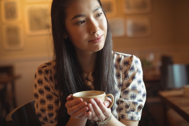 Femme ayant une tasse de café au café