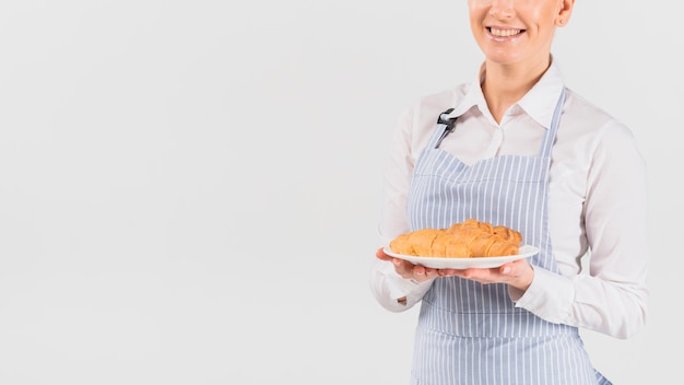 Femme Baker tenant une assiette avec croissant