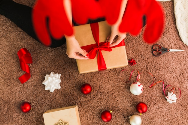 Femme en bandeau de bois de cerf avec coffret près de boules de Noël