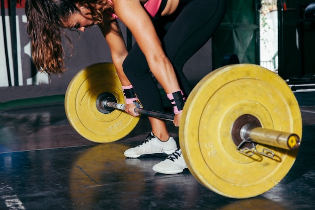 Femme avec barbell jaune dans la salle de gym