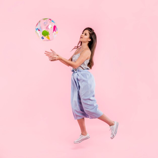 Femme en barboteuse jouant avec un ballon de plage