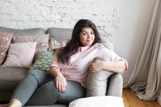 Une femme avec un beau corps pose sur le canapé