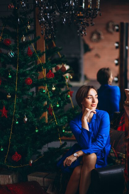 Femme en belle robe assise près d&#39;un arbre de Noël