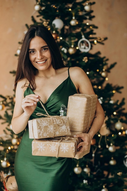 Femme en belle robe tenant des cadeaux de Noël