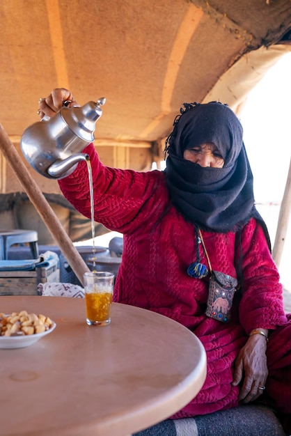 Photo gratuite une femme berbère prépare du thé pour des invités dans un camp du désert de merzouge.