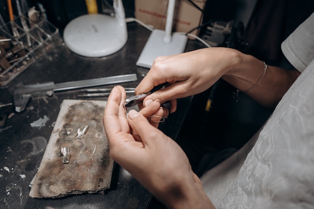 Femme bijoutier coupe un morceau de soudure avec des pinces