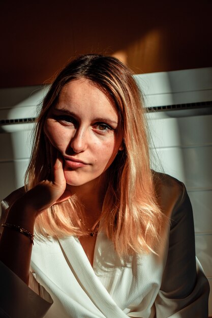 Femme en blanc près du mur blanc