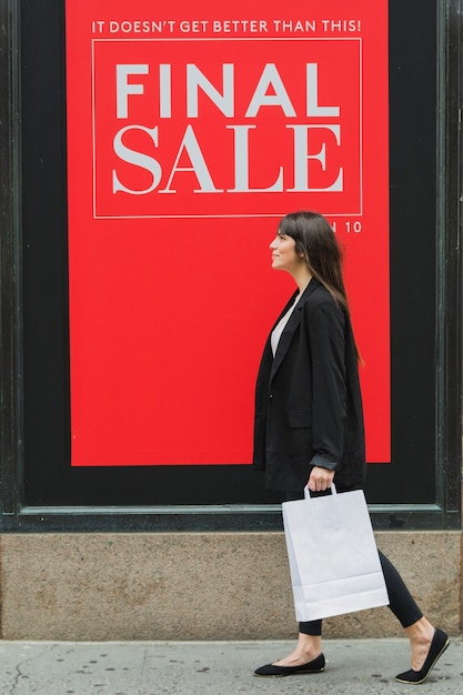 Femme, à, blanc, sac shopping, marche, près, magasin