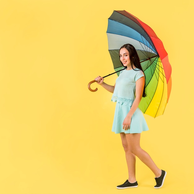 Femme en bleu avec parapluie arc-en-ciel