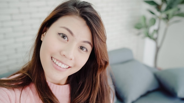 Femme blogueuse asiatique utilisant un smartphone enregistrant une vidéo vlog dans le salon à la maison