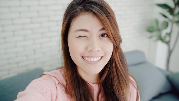 Femme blogueuse asiatique utilisant un smartphone enregistrant une vidéo vlog dans le salon à la maison