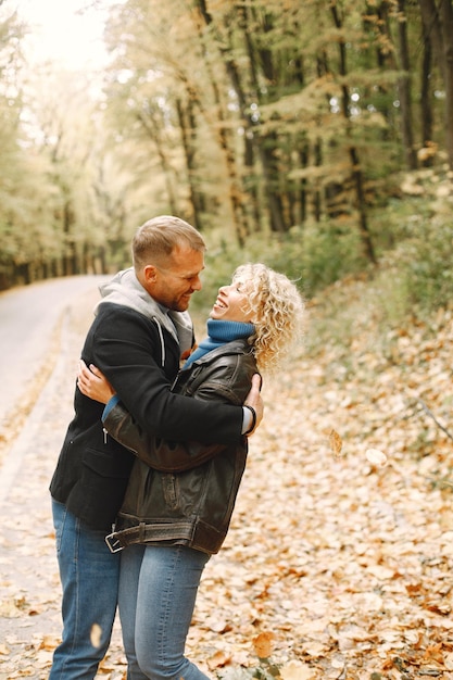 Femme blonde bouclée et homme debout dans la forêt d'automne et s'étreindre