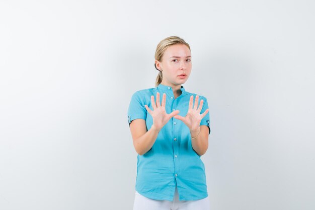 Photo gratuite femme blonde en chemisier bleu montrant un geste d'arrêt et ayant l'air effrayé