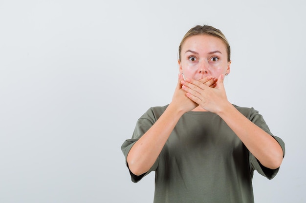 La femme blonde couvre sa bouche avec les mains sur fond blanc