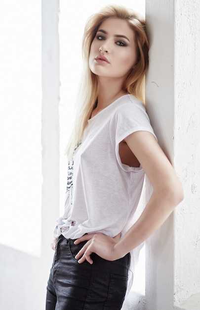 Femme blonde dans un t-shirt blanc posant dans une lumière.