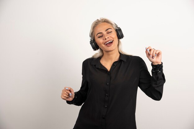 Femme blonde écoute la chanson avec des écouteurs sur fond blanc. Photo de haute qualité