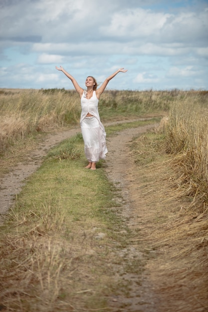 Femme blonde insouciante, debout sur le chemin du champ